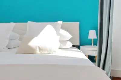 a white bed with white pillows and a blue wall at Fontana di Trevi dream home in Rome