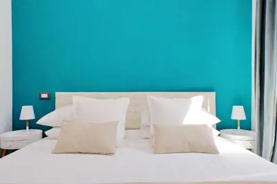 a bedroom with a white bed with a blue wall at Fontana di Trevi dream home in Rome