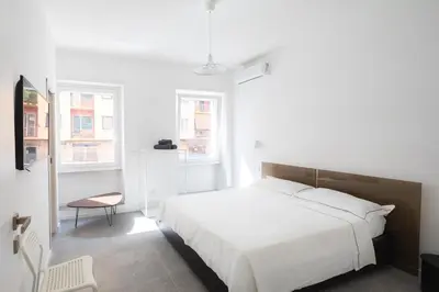 a bedroom with a white bed and two windows at Claudio Vaticano Home in Rome
