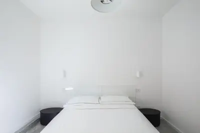 a white bed in a white room with two black containers at Claudio Vaticano Home in Rome