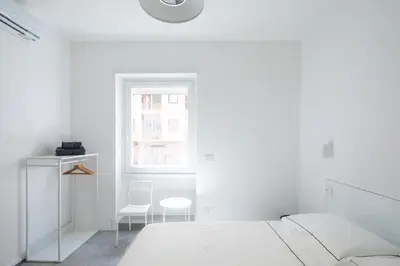 a white bedroom with a bed and a chair at Claudio Vaticano Home in Rome