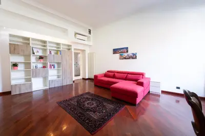 a living room with a red couch and a rug at Casa Aosta in Rome