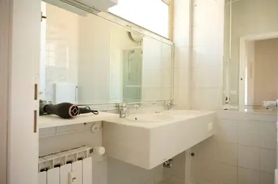 a white bathroom with a sink and a mirror at Riboty 21 in Rome