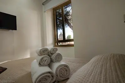 a pile of towels on a bed with a window at The Little Big House in Rome