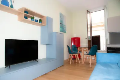 a living room with a tv and a table with chairs at Barberini Bright Apartment in Rome