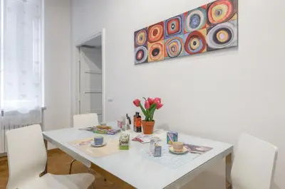 a white dining room table with white chairs and a painting at Casa Tua a Monti in Rome