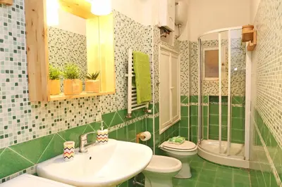 a green and white bathroom with a sink and a toilet at Casa Tua a Monti in Rome