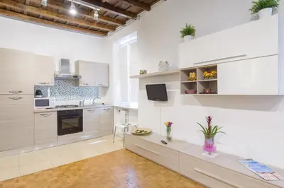 a kitchen with white cabinets and a table in it at Casa Tua a Monti in Rome