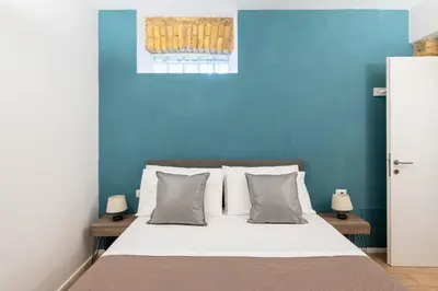 a blue bedroom with a bed with white sheets and pillows at SuityRHome San Pietro 99 in Rome