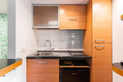 a kitchen with wooden cabinets and a sink at Studio Suite Aurelia Antica in Rome