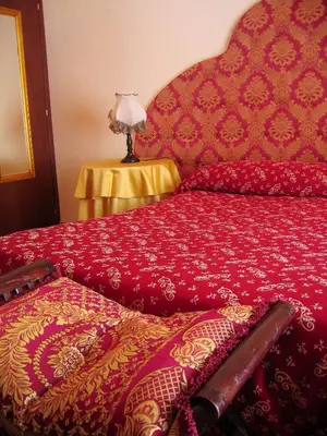 a bed with a red comforter and a lamp on a table at Alloggio Turistico in Rome
