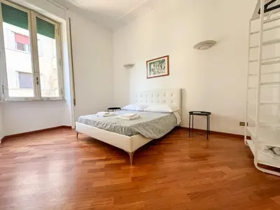 a white bedroom with a bed and a wooden floor at Montezebio Boutique Apartment in Rome