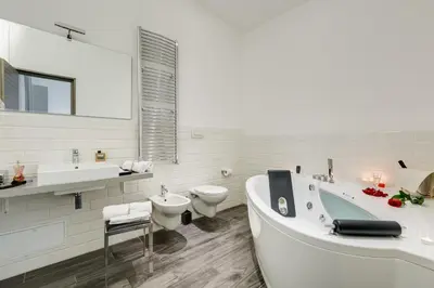 a white bathroom with a tub and two sinks and a toilet at Relais Colonna in Rome