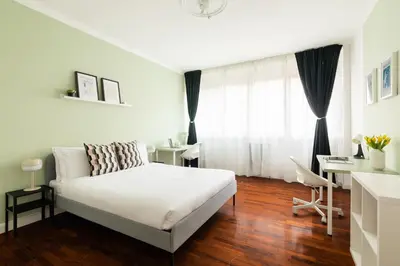 a white bedroom with a bed and a desk at Domiziano Boutique Apartment in Rome