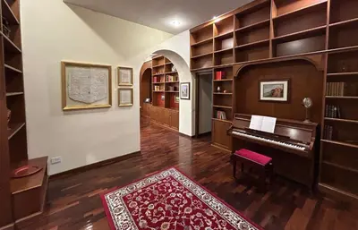 a living room with a piano in a library at Colosseum's Custodian - Apartment 115 m2 in Rome