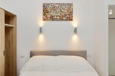 a bedroom with a bed with a painting on the wall at suity I cozy barberini studio in Rome