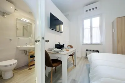 a white room with a bed and a desk and a sink at suity I cozy barberini studio in Rome