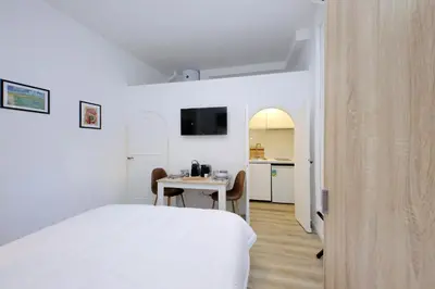 a bedroom with a bed and a table and a kitchen at suity I cozy barberini studio in Rome