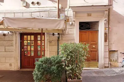 an entrance to a building with awning and two bushes at suity I cozy barberini studio in Rome