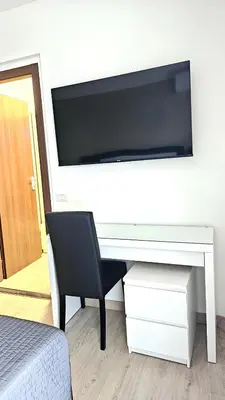 a white desk with a chair and a television on a wall at Convenient Booking B&B in Rome
