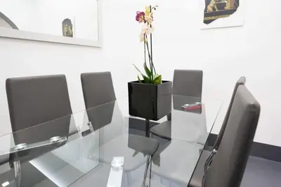 a glass table with chairs and a vase with a plant at White Style Gambero in Rome