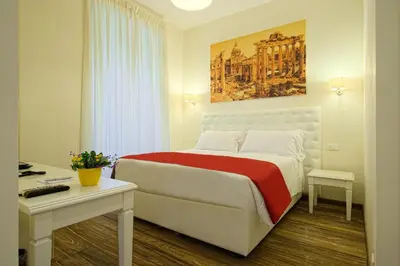 a bedroom with a bed and a desk and a painting at Star Vatican Rooms in Rome