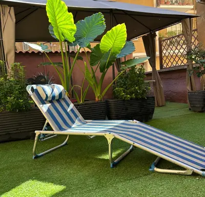a blue and white chair sitting on the grass at Candelor House - Apartment & Garden in Gianicolense in Rome
