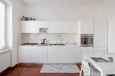 a white kitchen with white cabinets and a table at Domus Alberone in Rome