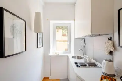 a white kitchen with a sink and a window at Domus Paolina in Rome