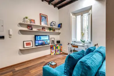 a living room with a blue couch and a tv at Vicolo leopardo suite Trastevere in Rome