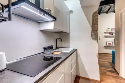 a kitchen with white cabinets and a black counter top at Vicolo leopardo suite Trastevere in Rome