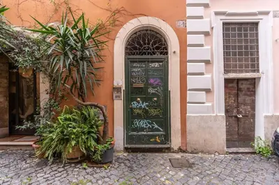 a green door with graffiti on it next to a building at Vicolo leopardo suite Trastevere in Rome