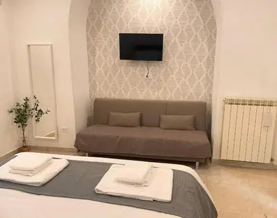 a bedroom with a bed and a couch with a flat screen tv at The Room 15 in Rome