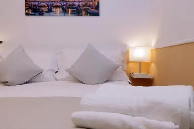 a bedroom with a white bed with pillows and a lamp at Trevi Feddy's Apartment in Rome