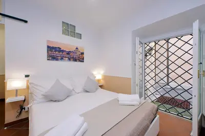 a white bed in a room with a window at Trevi Feddy's Apartment in Rome