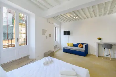 a white room with a bed and a blue couch at Monserrato Charme Apartment - Campo dei Fiori in Rome