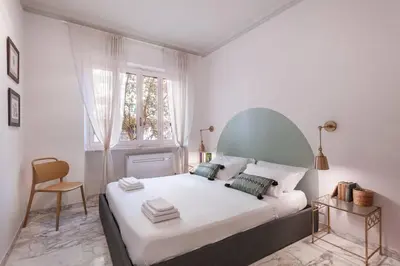a bedroom with a white bed with a chair and a window at laDolceVita - Flaminio Stylish Flat in Rome