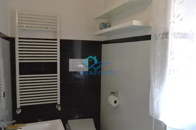 a bathroom with a white toilet and a black tile wall at Your Roman Retreat near San Giovanni in Rome