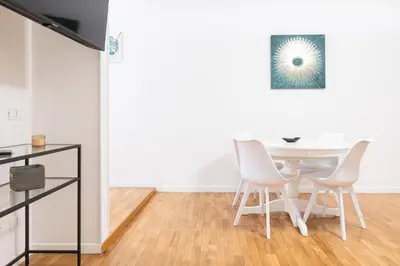 a white dining room with a table and chairs at Mosaic Trastevere Silver Apartment in Rome