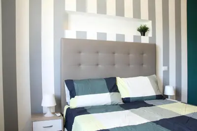 a bedroom with a bed with a striped wall at Capital House Roma in Rome