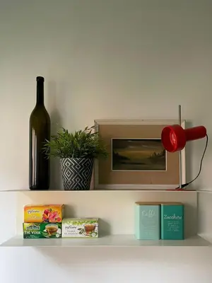 a shelf with a bottle of wine and a clock at Fabiola Holiday House in Rome