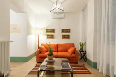 an orange couch in a living room with a table at Popolo Charming Apartment in Rome