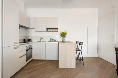 a kitchen with white cabinets and a counter with chairs at Trastevere Contemporary Apartment in Rome