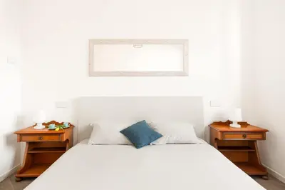 a white bedroom with two nightstands and a bed at Trastevere Contemporary Apartment in Rome