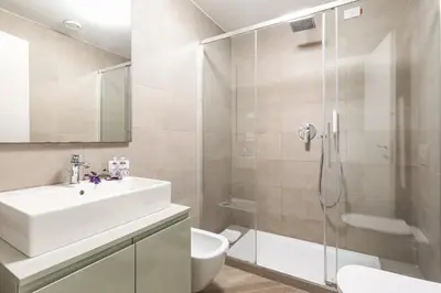 a bathroom with a white sink and a shower at Trastevere Contemporary Apartment in Rome