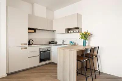 a kitchen with white cabinets and a wooden table at Trastevere Contemporary Apartment in Rome