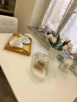 a table with a vase of flowers and a tray with cups and coffeeisers at MARAND HOUSE ROME in Rome