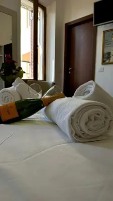 a bottle of wine sitting on a bed with towels at Romerooms Condotti in Rome