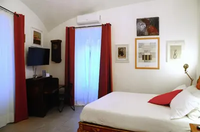 a bedroom with a bed with red curtains and a television at House of Cardinals in Rome