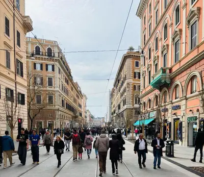 a group of people walking down a city street at House of Cardinals in Rome